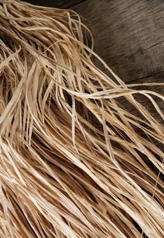 close up view of the top of a straw grass covering on a wooden surface with wood planks in the background