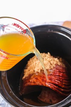 someone pouring orange juice into a crock pot filled with cooked meat and brown rice