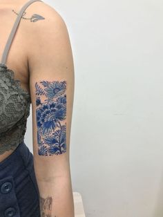 a woman's arm with a blue flower tattoo on her left arm and shoulder