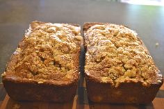 two loafs of banana bread sitting on top of a wooden cutting board next to each other