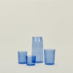 three blue glass vases sitting next to each other on a white surface with no one around them