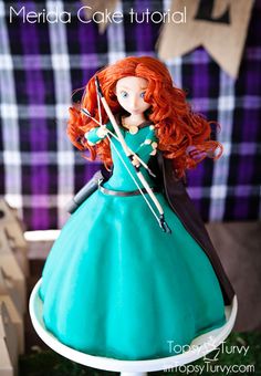 a doll with red hair holding a bow and arrow on top of a cake stand