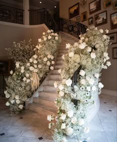 the staircase is decorated with white flowers and greenery