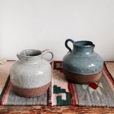 two vases sitting on top of a rug next to each other