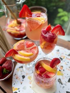 three glasses filled with different types of fruit on top of a table next to plates and utensils