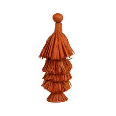 an orange vase with some tassels on the top and bottom, sitting in front of a white background