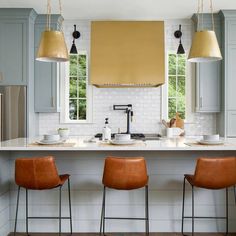 three brown leather chairs sitting on top of a kitchen counter