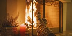 a person with their feet up in front of a fire place and a lit candle