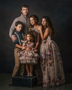 a family posing for a portrait in front of a dark background with their arms around each other