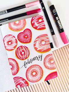 a notebook with pink and yellow donuts on it next to markers, pencils and marker