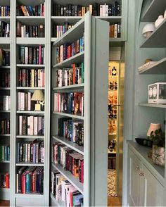 an open bookcase with many books on it in a room filled with white cupboards