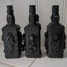 three black bottles with skulls and gears on them