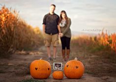 a couple standing next to pumpkins on a dirt road