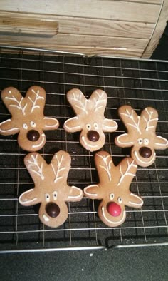 four decorated cookies with reindeer faces on a cooling rack