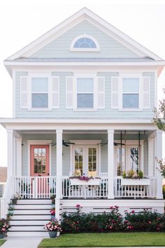 a white house with flowers in the front yard and steps leading up to the porch