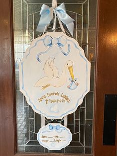 a door hanger with a stork holding a baby's first christmas ornament