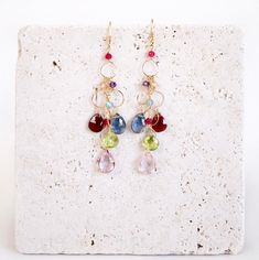 Free Shipping on our Rainbow Chandelier Earrings. Made with a waterfall of colorful gemstones. - Pink Clear Quartz, Iolite, Peridot and Garnet - 14k Gold Plated .925 Italian Fine Silver - 2 3/4 Inches long - French Hooks (with safety backs) - Handmade in the USA - Arrives in a gift box Please note, each pair is entirely unique and one of a kind due to the natural variances in the gemstones. They may vary slightly from the pair shown in the image. Our jewelry is packaged with extreme care so it w Peridot And Garnet, Peridot Dangle Earrings, Statement Earrings Wedding, Gold Circle Necklace, Gold Chandelier Earrings, Gemstone Drop Earrings, Rainbow Gemstones, Earrings Colorful, Rainbow Earrings