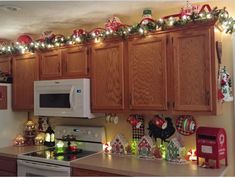 a kitchen decorated for christmas with lights on the cabinets and garland hanging from the ceiling