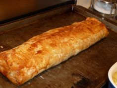 a large piece of bread sitting on top of a pan next to a bowl of food