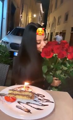 a woman sitting at a table with a piece of cake and flowers in front of her