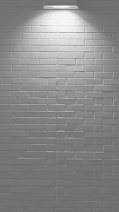 a black and white photo of a brick wall with a light on it's side