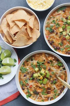 three bowls of mexican soup with tortilla chips and avocado on the side