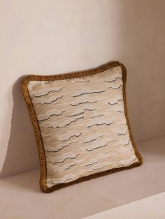 a pillow sitting on top of a white shelf next to a wall with a wooden frame