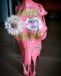 a pink cow statue with a flower on it's head and words that say, biscuits gravy