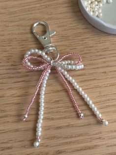 a keychain with pearls and a bow on it sitting on a wooden table