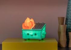 a green toaster sitting on top of a yellow table next to vases and a lamp