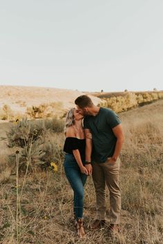 a man and woman kissing in the middle of a field