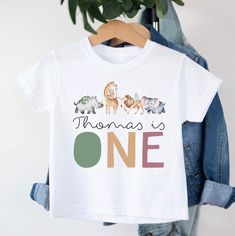 Personalised First Birthday Safari T-shirt T-shirt is 100% cotton.  We design & print our products with care & love! We use the best quality vinyls, inks & transfers on all products. * * * * * * * * * * * * * * * * * * * * * * * * * * * * * CARE INSTRUCTIONS: Wash inside out on gentle wash, Do not tumble dry. * * * * * * * * * * * * * * * * * * * * * * * * * * * * * SHIPPING: We want to get your product to you as quickly as possible, your purchase will be shipped through Australia post, Express post is available for selection. * * * * * * * * * * * * * * * * * * * * * * * * * * * * * GUARANTEE: We stand behind our products with a 100% guarantee; if you are unsatisfied with our product, please let us know & we will rectify any issues. We are unable to refund products due to change of mind o First Birthday Graphic Tee With Crew Neck, First Birthday Graphic Tee With Name Print, Graphic Tee With Name Print For First Birthday, Cotton T-shirt With Character Print For Birthday Gift, White Character Print Top For Birthday Gift, Custom Print White T-shirt For First Birthday, Birthday T-shirt With Name Print, Short Sleeve, White Custom Print T-shirt For First Birthday, Birthday Name Print Short Sleeve T-shirt