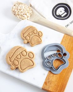 three cookie cutters on a cutting board with dog paw prints and oatmeal in the background