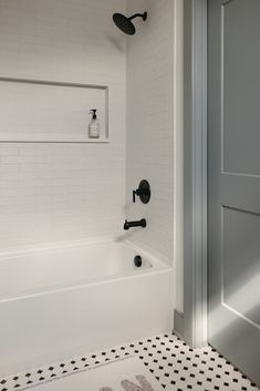 a bathroom with a black and white checkered floor, shower head, and bathtub