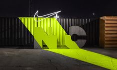 the neon green nike logo is lit up in front of a shipping container at night