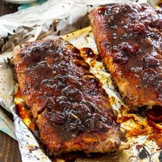 two ribs covered in bbq sauce sitting on top of tin foil