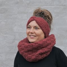 a woman wearing a red knitted cowl with a messy bun in front of a gray wall