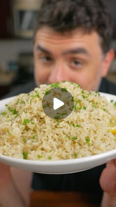 a man holding a white plate with rice and lemons on it in front of his face