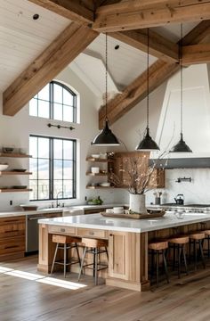 an open kitchen with wooden beams and white counter tops, along with stools that match the hardwood flooring