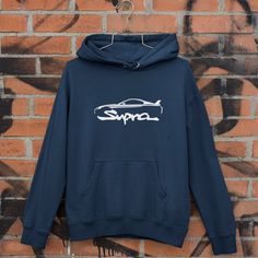 a blue hoodie with the word supro on it hanging against a brick wall