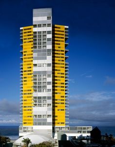 a tall yellow and white building next to the ocean