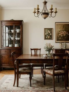 a dining room table and chairs in front of a china cabinet