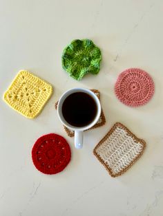 four crocheted coasters and a cup of coffee on a white table top