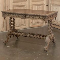 an old wooden table sitting on top of a floor next to a wall with doors in the background