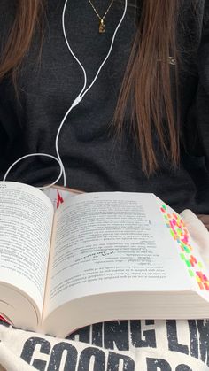 a girl is reading a book and listening to headphones