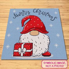 a cross stitch christmas card with a santa clause holding a gift box and the words merry christmas