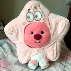 a pink stuffed animal with googly eyes sitting on a bed