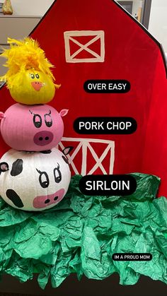 two paper mache pigs sitting on top of each other in front of a red barn