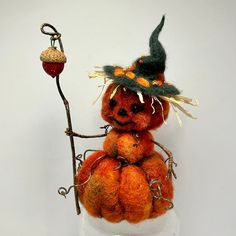 an orange stuffed pumpkin with a witch's hat holding a broom and acorn