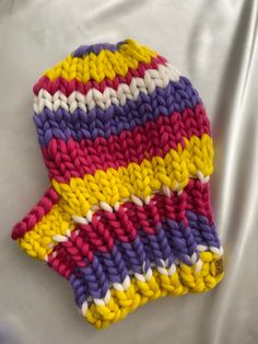 a multicolored knitted hat laying on top of a white sheet